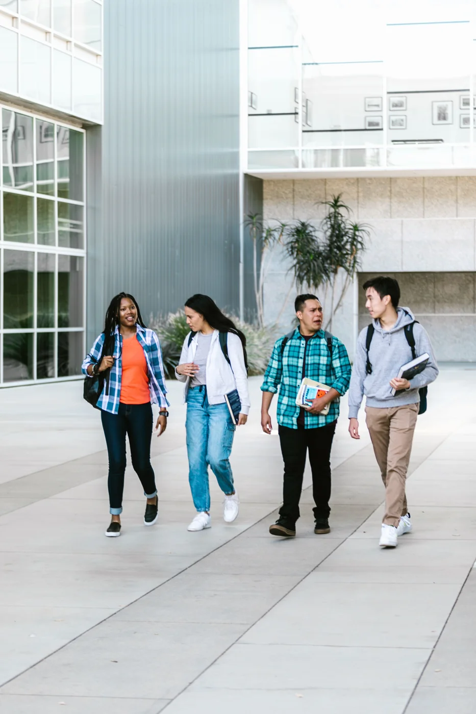 Four students walking together outdoors on a college campus